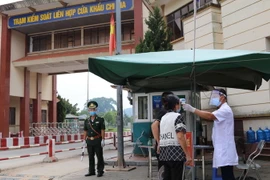 Lực lượng chức năng kiểm tra y tế đối với người vào khu vực cửa khẩu Chi Ma. (Ảnh: Quang Duy/TTXVN)