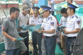 Lực lượng Vùng Cảnh sát biển trực tiếp phát tờ rơi tuyên truyền các quy định tới ngư dân. (Ảnh: TTXVN phát)