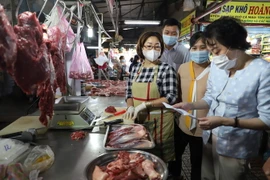 Cán bộ Ban quản lý kiểm tra chứng từ chứng minh nguồn gốc thực phẩm của tiểu thương tại chợ Phạm Văn Hai, Thành phố Hồ Chí Minh. (Ảnh: Hồng Giang /TTXVN)