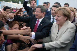 Thủ tướng Đức Angela Merkel (phải) và Thủ tướng Thổ Nhĩ Kỳ Ahmet Davutoglu gặp gỡ những người tị nạn trong chuyến thăm Gaziantep. (Nguồn: THX/TTXVN)
