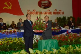 Nguyên Tổng Bí thư Chummaly Sayasone (trái) tặng hoa cho ông Bounnhang Volachith. (Ảnh: Phạm Kiên/TTXVN)