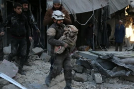 Nhân viên dân sự Syria chuyển một em nhỏ bị thương trong các cuộc giao tranh giữa quân đội chính phủ và phiến quân IS. (Ảnh: AFP/TTXVN)
