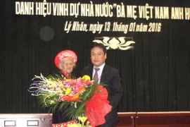 Phó Chủ tịch UBND tỉnh Hà Nam Vũ Đại Thắng tặng hoa Bà mẹ Việt Nam Anh hùng Trần Thị Tuyết. (Ảnh: TTXVN)