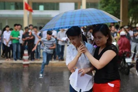 Thí sinh rời trường thi môn Vật lý ở Hà Nội dưới trời mưa. (Ảnh: Lê Minh Sơn/Vietnam+)