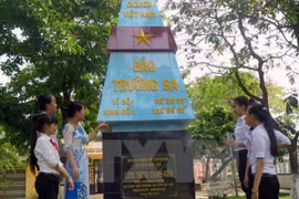 Giáo viên giới thiệu cho học sinh Trường THCS Mỹ Hòa các thông tin về vĩ độ, kinh độ của đảo Trường Sa trên cột mốc mô phỏng. (Ảnh: Đỗ Trưởng/TTXVN)