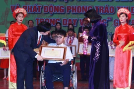 Bộ trưởng Phùng Xuân Nhạ và Phó Chủ tịch nước Đặng Thị Ngọc Thịnh trao hoa và bằng khen cho em Nguyễn Thiên Phú. (Ảnh: Quý Trung/TTXVN)