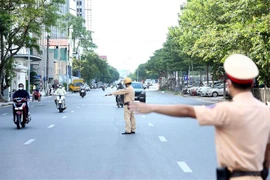 Lực lượng CSGT yêu cầu các phương tiện tham gia giao thông dừng lại kiểm tra giấy tờ khi đi qua chốt liên ngành tại tuyến phố Trần Quang Khải (quận Hoàn Kiếm). (Ảnh: Phạm Kiên/TTXVN)