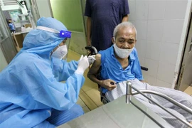 Các y bác sỹ bệnh viện Phú Nhuận thực hiện tiêm vaccine cho người trên 65 tuổi, người có bệnh nền tại Trung tâm y tế phường 11, quận Phú Nhuận. (Ảnh: Thanh Vũ/TTXVN)