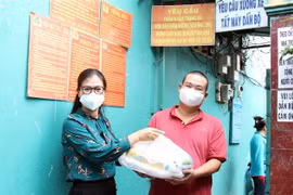 Đại diện Ủy ban MTTQ Việt Nam TP trao quà cho lao động nghèo, gặp khó khăn do ảnh hưởng dịch bệnh COVID-19 tại phường Hiệp Thành, Quận 12. (Ảnh: Xuân Khu/TTXVN)