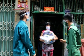 Các chiến sỹ Trung đoàn 88, Sư đoàn 302 (Quân Khu 7) cùng với Ban Chỉ huy quân sự phường 8, Quận 10 trao tặng lượng thực, thực phẩm tận nhà cho người lao động nghèo hẻm 139 Nguyễn Tiểu La, Quận 10. (Ảnh: Thanh Vũ /TTXVN)