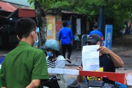 Người đi đường đi qua chốt kiểm dịch dều phải xuất trình giấy đi dường và đứng xa cách 2m. (Ảnh: Tuấn Anh/TTXVN)