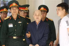  Lực lượng chức năng dẫn giải bị cáo Đinh Ngọc Hệ vào phiên xét xử. (Ảnh: Doãn Tấn/TTXVN)