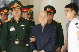  Lực lượng chức năng dẫn giải bị cáo Đinh Ngọc Hệ vào phiên xét xử. (Ảnh: Doãn Tấn/TTXVN)