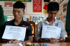 Hai đối tượng bị bắt cùng tang vật. (Ảnh: TTXVN phát)