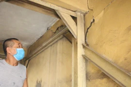 Ông Nguyễn Quang Gắng, tổ phó tổ dân phố chỉ ra các vết nứt cho thấy các bức tường đã nghiêng, dẫn đến nứt tách hàng loạt. (Ảnh: Minh Anh/Vietnam+)