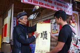 Ông đồ tặng chữ, giải nghĩa chữ đầu Xuân tại khu Hồ Văn (Văn Miếu-Quốc Tử Giám) trong ngày khai mạc. (Ảnh: Thanh Tùng/TTXVN)
