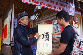 Ông đồ tặng chữ, giải nghĩa chữ đầu Xuân tại khu Hồ Văn (Văn Miếu-Quốc Tử Giám) trong ngày khai mạc. (Ảnh: Thanh Tùng/TTXVN)