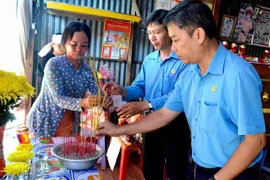 Phó Chủ tịch Liên đoàn Lao động tỉnh An Giang Nguyễn Hữu Giang (bìa phải) thắp hương chia buồn cùng gia đình nạn nhân Nguyễn Văn Út. (Ảnh: Công Mạo/TTXVN)