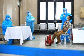 Nhân viên y tế lấy mẫu xét nghiệm nhanh COVID-19 cho những hành khách chưa xét nghiệm trước khi lên tàu. (Ảnh: Thành Đạt/TTXVN)