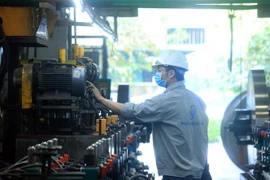 Công nhân vận hành thiết bị máy móc trên dây chuyền sản xuất tôn inox. (Nguồn: TTXVN)