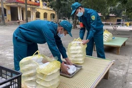 Chiến sỹ dân quân tự vệ ở khu cách ly y tế tập trung Trường THPT Nguyễn Thị Giang, huyện Vĩnh Tường (Vĩnh Phúc) chuẩn bị suất ăn cho người dân trong khu cách ly tập trung. (Ảnh: TTXVN phát)