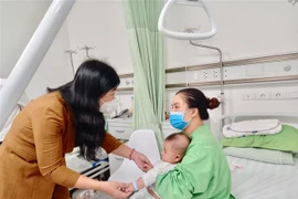 Chủ tịch Ủy ban Mặt trận Tổ quốc Việt Nam thành phố Hà Nội Nguyễn Lan Hương ân cần thăm hỏi, động viên từng gia đình các cháu bé. (Ảnh: TTXVN phát)