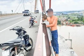 Anh P. ôm con trai trèo ra lan can cầu Cần Thơ định tự tử. (Ảnh: TTXVN phát)