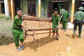 Các chiến sỹ công an huyện Hương Khê (Hà Tĩnh) chung tay dọn vệ sinh môi trường sau lũ tại xã Hương Đô. (Ảnh: Phan Quân/TTXVN)