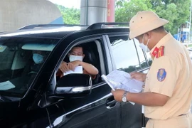Cảnh sát giao thông kiểm tra giấy tờ của người dân khi di chuyển qua chốt kiểm soát liên ngành phòng, chống dịch COVID-19 Dốc Xây, thị xã Bỉm Sơn. (Ảnh: Nguyễn Nam/TTXVN)
