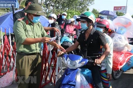 Lực lượng chức năng kiểm tra giấy tờ của người dân khi qua chốt kiểm soát dịch trên Quốc lộ 1. (Ảnh: Bùi Giang/TTXVN)