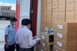 Đại diện Ủy ban Mặt trận Tổ quốc Việt Nam Thành phố Hồ Chí Minh và lực lượng hải quan kiểm tra, lấy mẫu lô sữa để hoàn thiện thủ tục thông quan. (Ảnh: TTXVN phát)