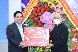 Thủ tướng Phạm Minh Chính tặng quà chúc mừng Giáng sinh giáo dân giáo xứ Long Hưng. (Ảnh: Dương Giang/TTXVN)