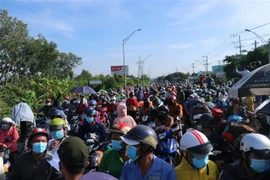 Hàng ngàn người dân chờ đợi qua chốt kiểm soát dịch trên Quốc lộ 1 (giáp ranh Long An-Tiền Giang) để về quê. (Ảnh: Bùi Giang/TTXVN)