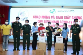 Lãnh đạo Tổng cục Hậu cần và Bệnh viện Quân y 175 trao giấy chứng nhận ra viện và tặng hoa chúc mừng hai bệnh nhân. (Ảnh: Hồng Pha/TTXVN phát)