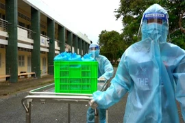 Điều dưỡng ở cơ sở cách ly Ký túc xá A, Đại học Cần Thơ mang cơm đến cho người dân đang cách ly. (Ảnh: Thu Hiền/TTXVN)