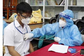 Khám sàng lọc cho học sinh trước khi tiêm vaccine phòng COVID-19. (Ảnh: Đồng Thúy/TTXVN)