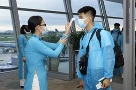 Kiểm tra nhiệt độ của hành khách trước khi lên máy bay. (Ảnh: Huy Hùng/TTXVN)