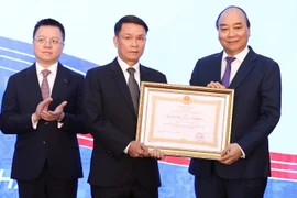 Thủ tướng Nguyễn Xuân Phúc, Chủ tịch Hội đồng Thi đua-Khen thưởng Trung ương, trao tặng Huân chương Lao động hạng Nhất cho Thông tấn xã Việt Nam. (Ảnh: Thống Nhất/TTXVN)
