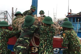 Bộ đội biên phòng Quảng Trị giúp ngư dân di chuyển ngư cụ chuẩn bị ứng phó với bão số 5. (Ảnh: Hồ Cầu/TTXVN)
