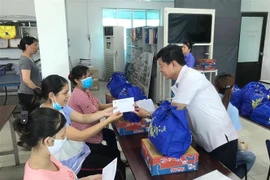 Trao tặng quà trị giá 200.000 đồng cùng 1 triệu đồng tiền mặt cho công nhân Công ty TNHH Pung Kook (Khu chế xuất Tân Thuận) bị mất việc làm. (Ảnh: Thanh Vũ/TTXVN)