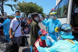 Đo thân nhiệt cho người dân bị kẹt lại Đà Nẵng do dịch trước giờ lên xe trở về quê. (Ảnh: Trần Lê Lâm/TTXVN)