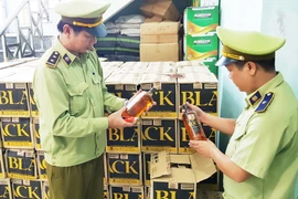 Lực lượng chức năng kiểm tra số rượu ngoại lậu vừa bắt giữ. (Ảnh: Võ Dung/TTXVN)