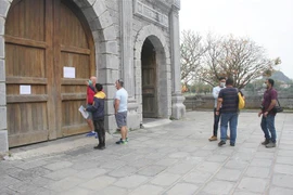 Khách tham quan đọc thông báo khi đến khu di tích. (Ảnh: Thùy Dung/TTXVN)