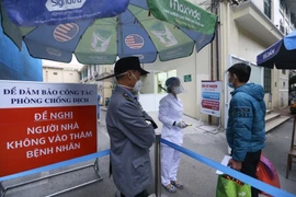 Người vào bệnh viện sẽ được kiểm tra thân nhiệt và khai báo lịch trình di chuyển. (Ảnh: Minh Quyết/TTXVN)