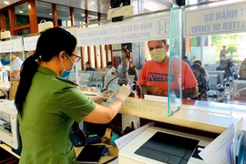 Cán bộ Công an cửa khẩu Tân Sơn Nhất chủ động trang bị đầy đủ khẩu trang, găng tay trong khi làm nhiệm vụ. (Ảnh: Thành Chung/TTXVN)