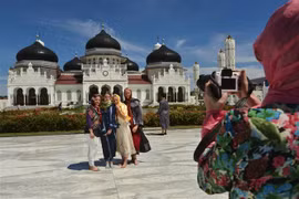Khách du lịch nước ngoài thăm nhà thờ Hồi giáo Baiturrahman ở Banda Aceh, Indonesia. (Ảnh: AFP/TTXVN)