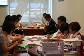 Các cán bộ Ban Đấu giá HNX đang kiểm tra hòm phiếu. (Ảnh: Doãn Đức/Vietnam+)