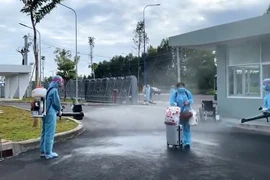 Phun khử khuẩn trước khi đưa công dân vào địa điểm cách ly tập trung tại Bình Dương. (Ảnh: Dương Chí Tưởng/TTXVN) 
