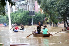 Người dân di thuyền qua khu vực ngập lụt sau mưa lớn tại Trung Quốc.(Ảnh: THX/ TTXVN)