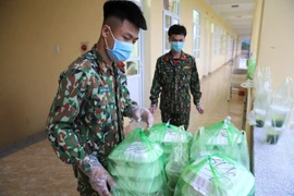 Các chiến sỹ hằng ngày mang cơm và nước uống cho công dân trong khu cách ly tập trung. (Ảnh: Thành Đạt/TTXVN)